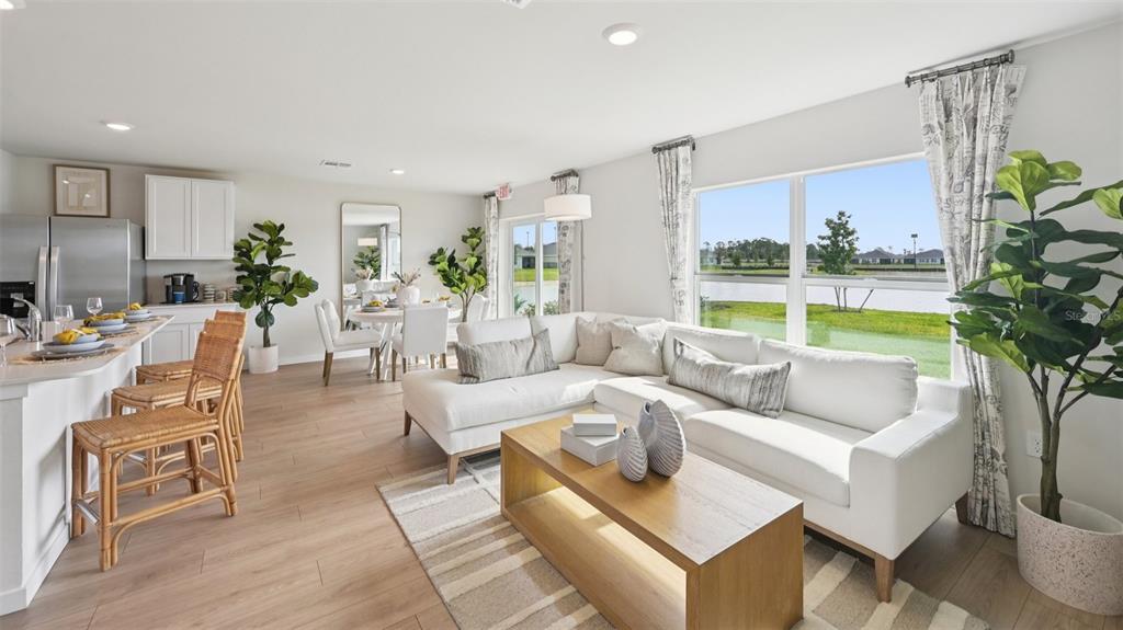 A bright open-concept living room features a white sectional sofa, kitchen island, and lake view — 1506 POWELL VALLEY DRIVE, PORT CHARLOTTE, FL