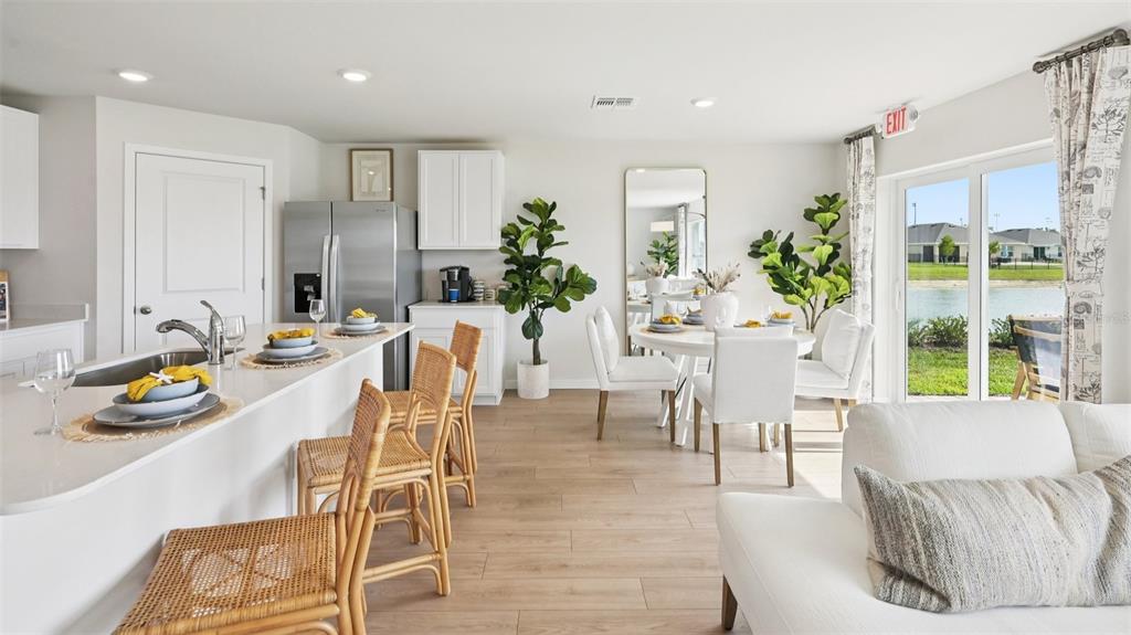 A bright, open-concept kitchen and dining area features light wood floors and water views — 1506 POWELL VALLEY DRIVE, PORT CHARLOTTE, FL