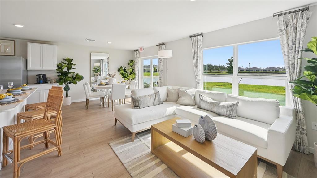 A bright open-concept living and dining area features light wood floors and water views — 1506 POWELL VALLEY DRIVE, PORT CHARLOTTE, FL