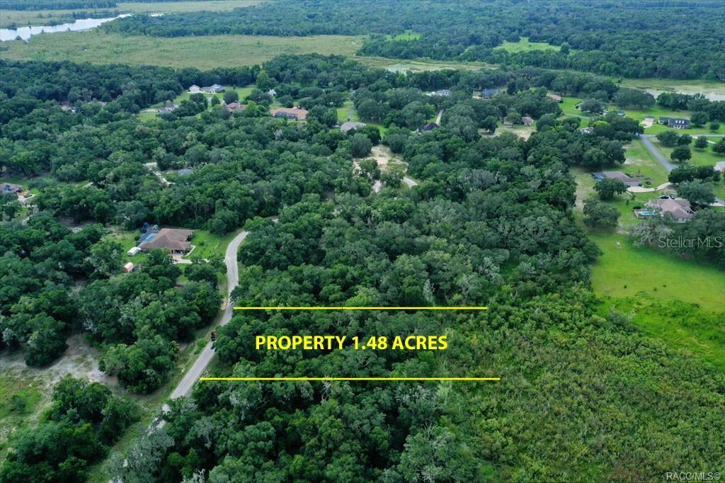 An aerial view shows a wooded 1.48-acre plot of land adjacent to a paved road — 4230 S KENVERA LOOP, INVERNESS, FL