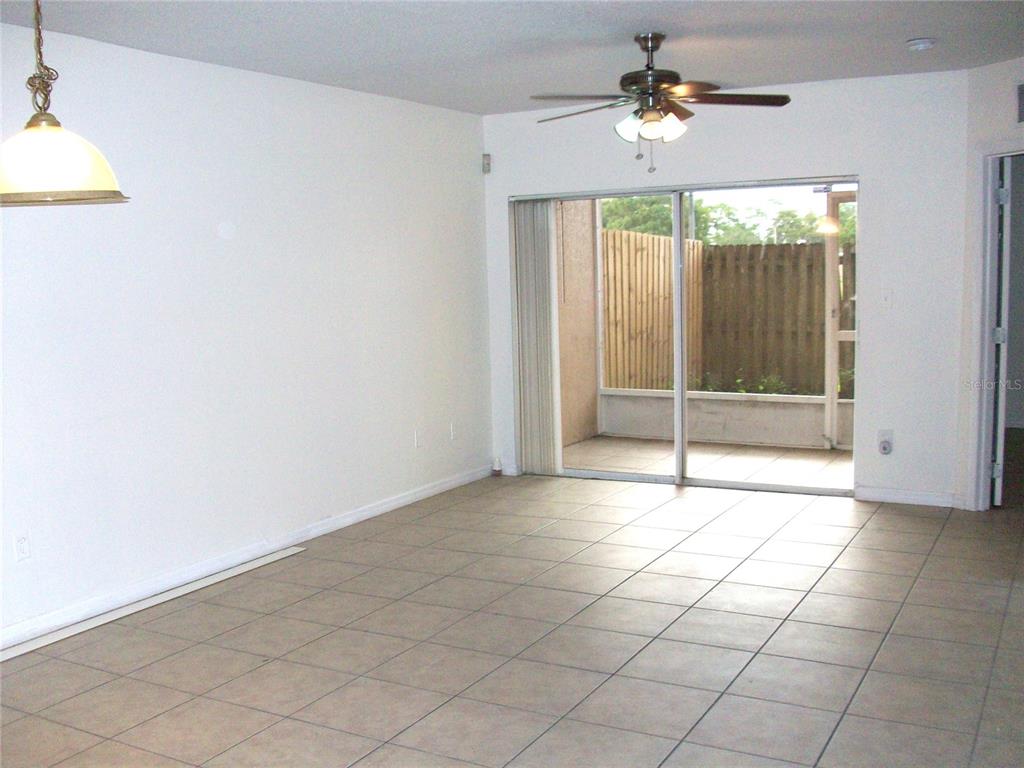 An empty room with light-colored tile flooring, a ceiling fan, and sliding glass doors — 495 LAS CORTES LANE UNIT 105, ORLANDO, FL