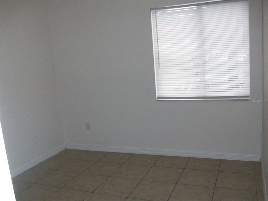 An empty room with light-colored walls, tile flooring, and a window with white blinds — 495 LAS CORTES LANE UNIT 105, ORLANDO, FL