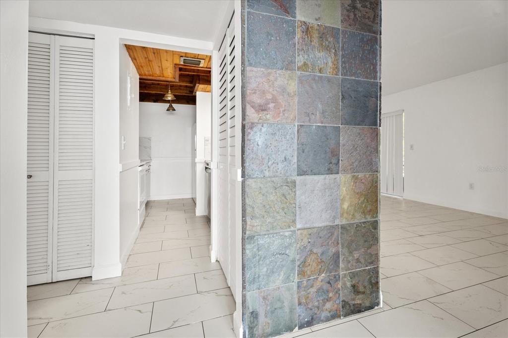 A tiled column separates a white-tiled living area from a kitchen with wood-paneled ceilings — 140 ORCHID WOODS COURT UNIT 7A, DELTONA, FL