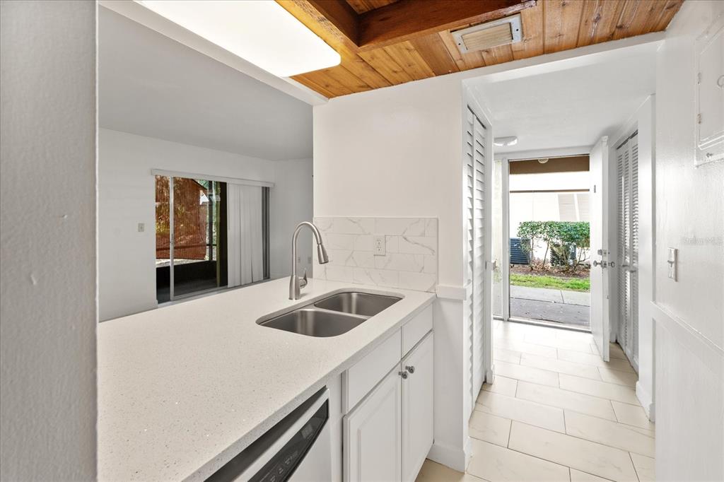 A kitchen with white countertops, a double sink, and a doorway leading to the outdoors — 140 ORCHID WOODS COURT UNIT 7A, DELTONA, FL
