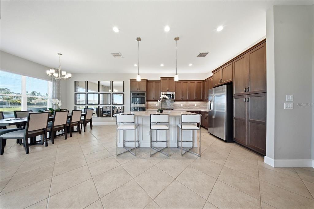 A kitchen and dining area with dark wood cabinets, a central island, and tiled floors — 15528 CORONA DEL MAR DRIVE, WIMAUMA, FL
