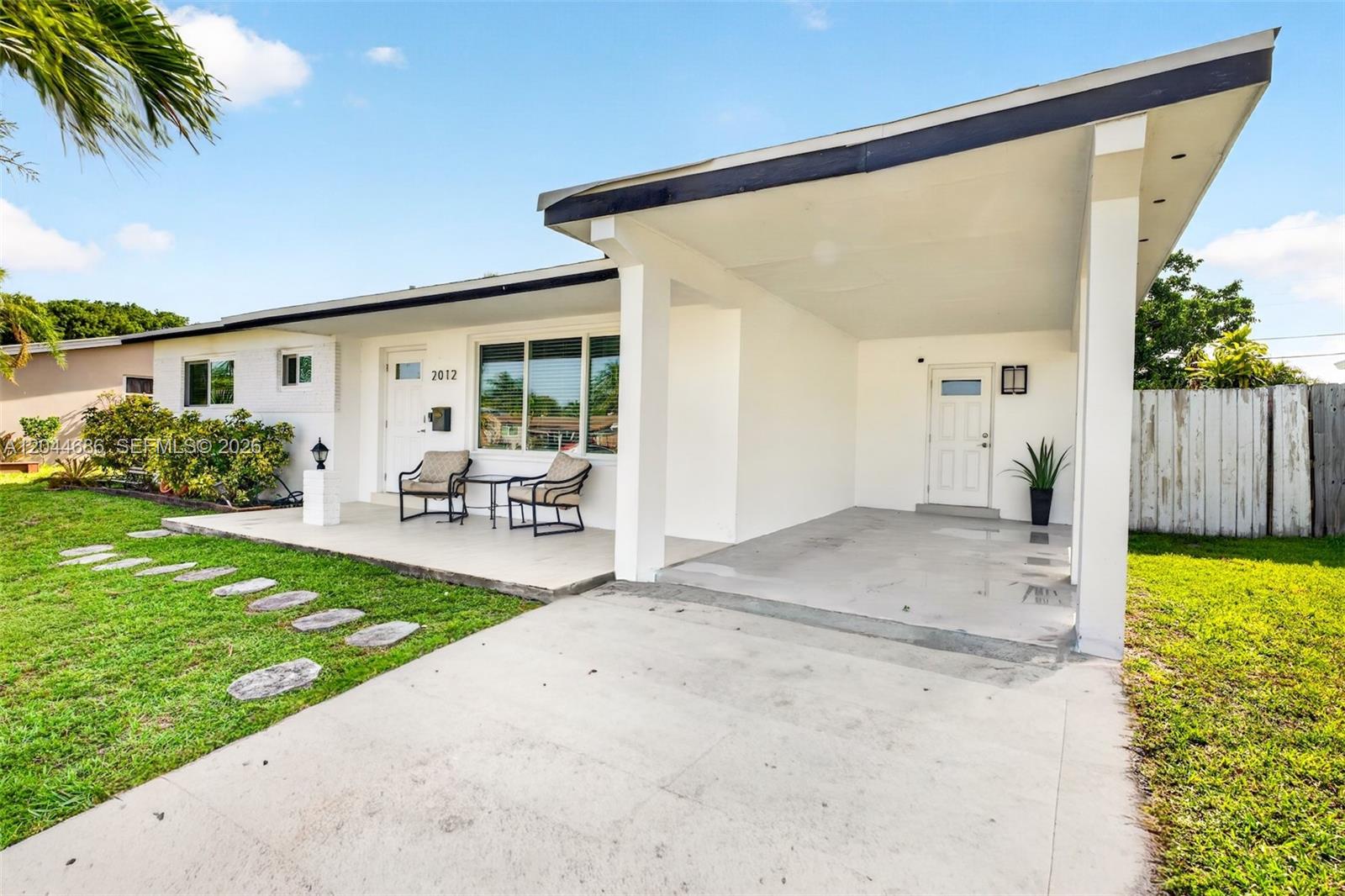 A white single-story house features a front porch, a carport, and a concrete driveway — 2012 N 31st Rd, Hollywood FL 33021, HOLLYWOOD, FL