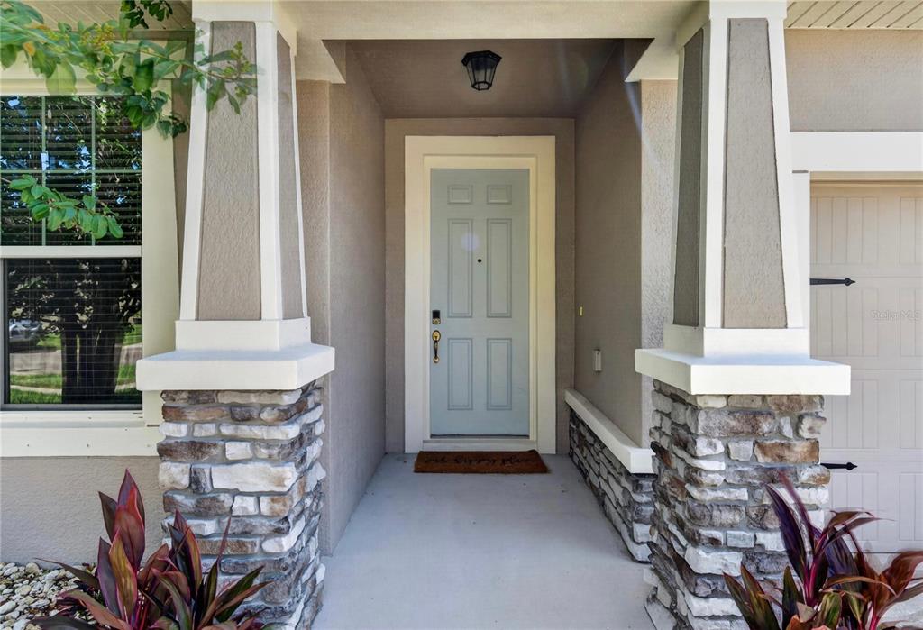 A front entryway features a light blue door, stone-based columns, and a concrete porch — 12209 W STREAMBED DRIVE, RIVERVIEW, FL
