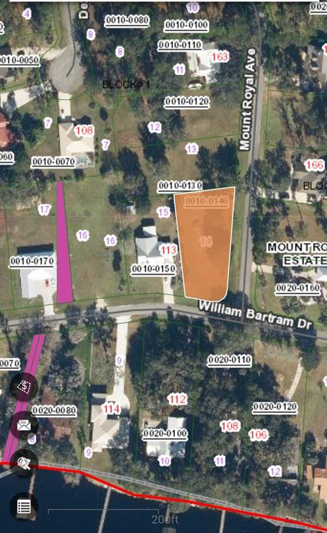 A large, grassy vacant lot features several tall trees and palm trees under a cloudy sky — 000 MOUNT ROYAL AVENUE, CRESCENT CITY, FL