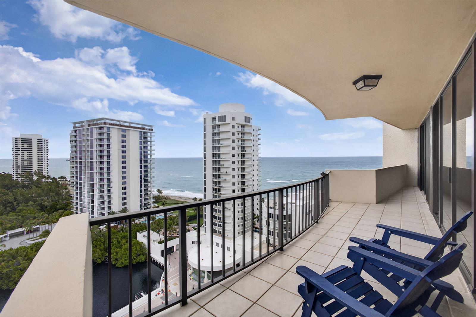 A balcony with two blue chairs overlooks the ocean and nearby high-rise buildings — 4200 N Ocean # 1706, Singer Island FL 33404, SINGER ISLAND, FL