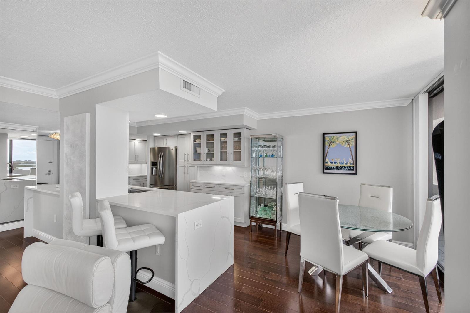 A modern kitchen and dining area with white cabinetry, quartz countertops, and dark hardwood floors — 4200 N Ocean # 1706, Singer Island FL 33404, SINGER ISLAND, FL