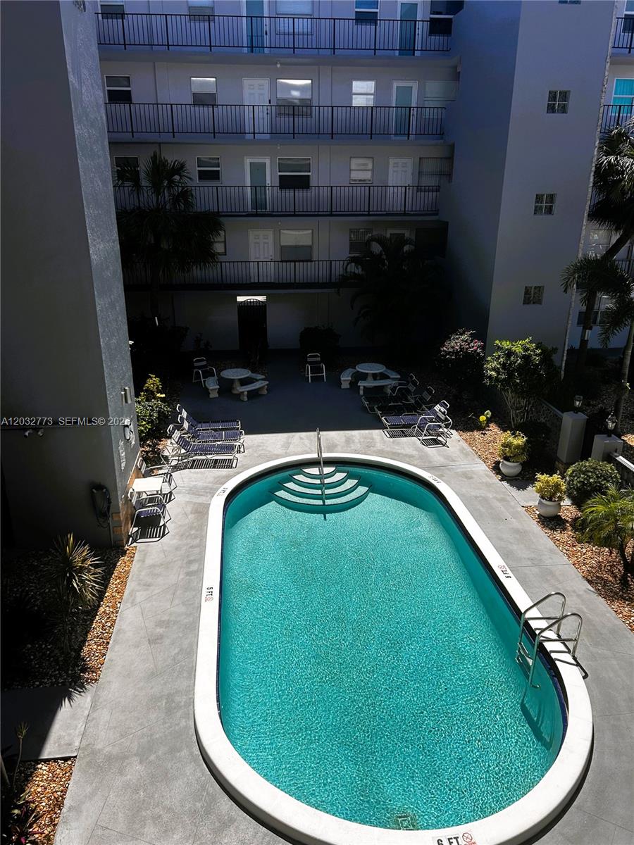 A living room features a beige sofa, a wooden coffee table, and a sunset wall painting — 1750 Jefferson St # 303, Hollywood FL 33020, HOLLYWOOD, FL