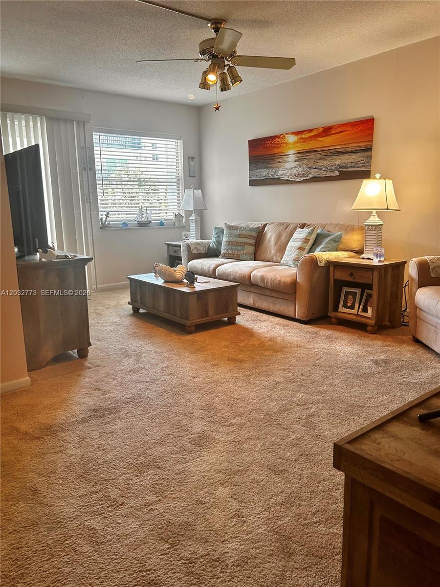 A living room features a beige sofa, a wooden coffee table, and a ceiling fan — 1750 Jefferson St # 303, Hollywood FL 33020, HOLLYWOOD, FL