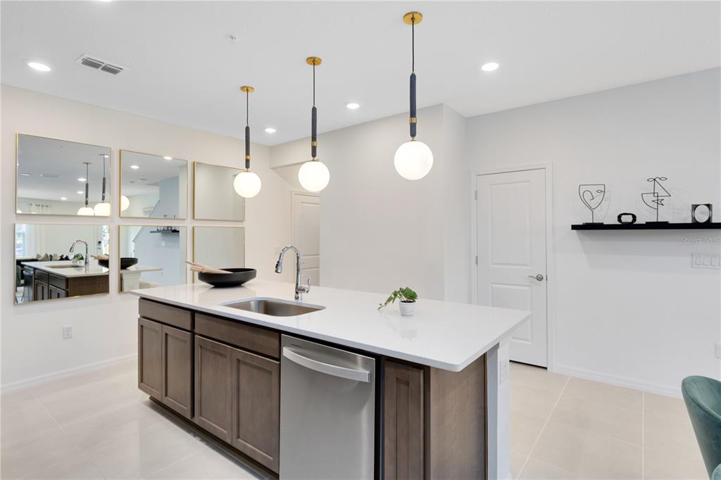 A kitchen island with a white countertop and stainless steel sink sits before wall mirrors — 11478 NONA SOUND ST, ORLANDO, FL