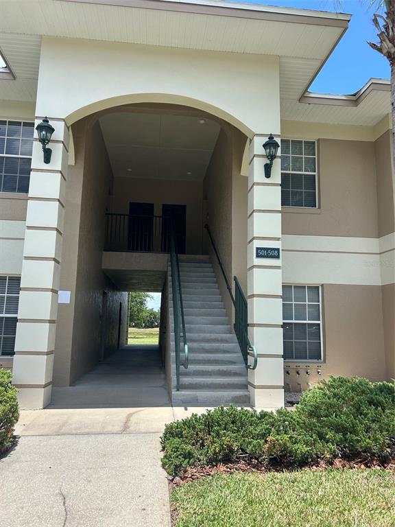 An exterior view of an apartment building entrance with stairs leading to upper-level units — 508 EAGLE POND DRIVE UNIT 508, WINTER HAVEN, FL