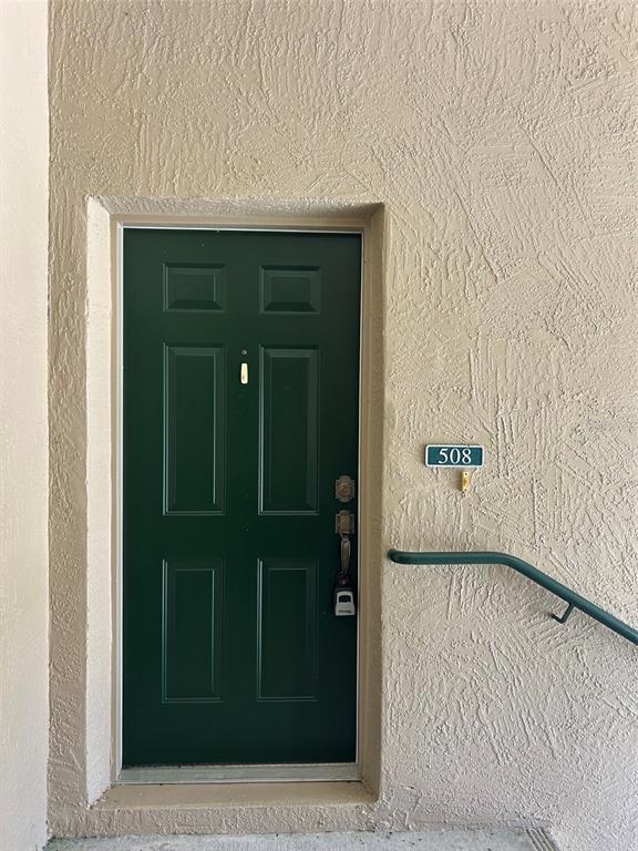 A dark green front door with a lockbox and unit number 508 on a textured wall — 508 EAGLE POND DRIVE UNIT 508, WINTER HAVEN, FL