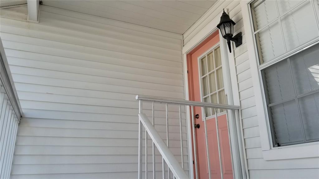 A pink front door with a window is set into white horizontal siding — 153 SUN ISLE CIRCLE, TREASURE ISLAND, FL