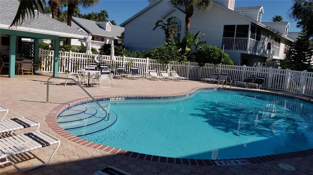 A swimming pool with a shallow entry area is surrounded by a patio and fence — 153 SUN ISLE CIRCLE, TREASURE ISLAND, FL