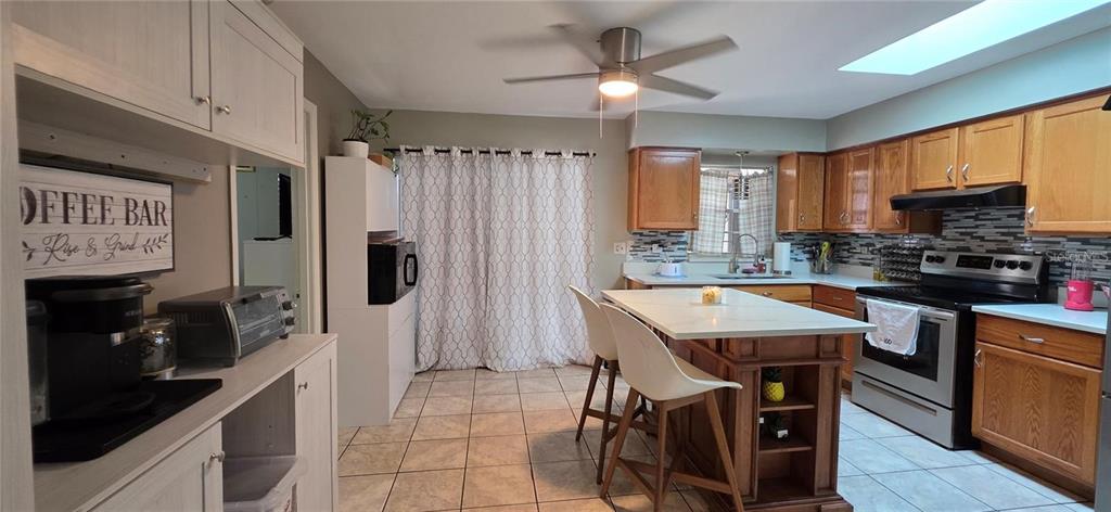 A kitchen features wood cabinets, a central island with seating, and a tiled floor — 1302 CENTER STREET, OCOEE, FL