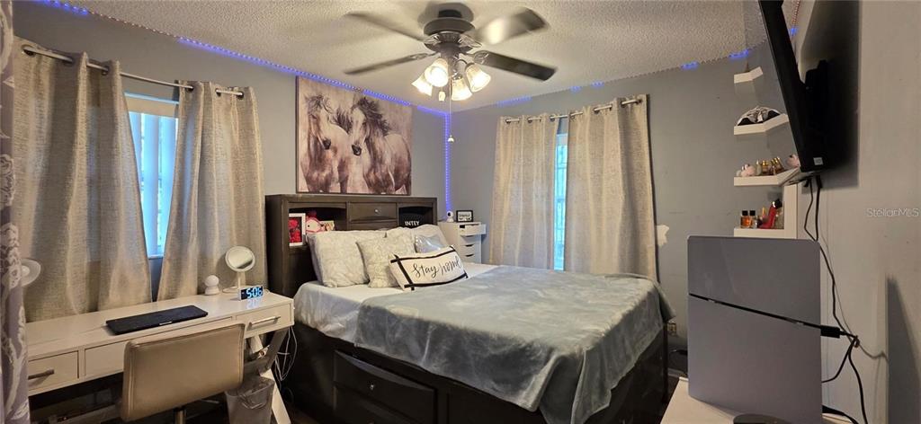 A bedroom features a bed with a headboard, a desk, and wall-mounted shelving — 1302 CENTER STREET, OCOEE, FL