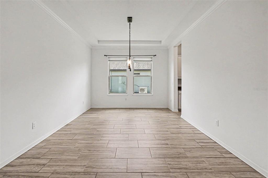 A dining room with light-colored tile flooring, white walls, and a modern pendant light fixture — 13065 BLISS LOOP, BRADENTON, FL