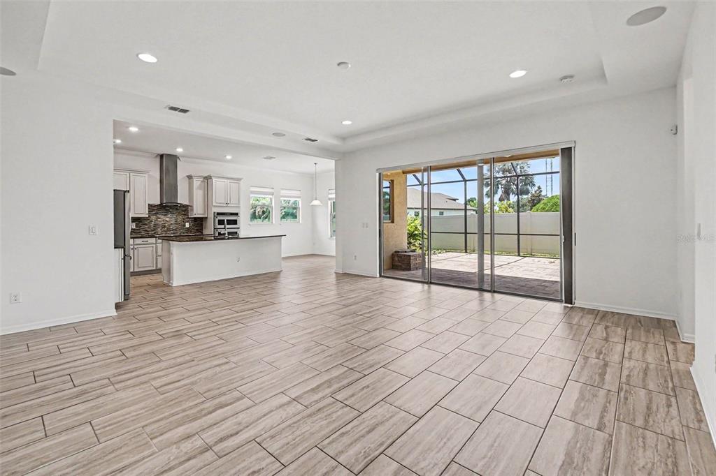 An open-concept living area with tile flooring, a kitchen, and sliding glass doors to a patio — 13065 BLISS LOOP, BRADENTON, FL