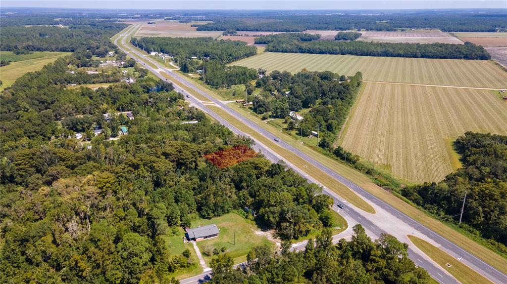 An aerial view shows a house surrounded by trees next to a divided highway and fields — 421 STATE ROAD 207 ROAD, EAST PALATKA, FL