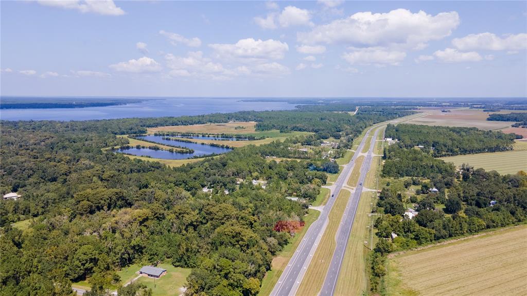 An aerial view shows a highway running past a large lake, forest, and open fields — 421 STATE ROAD 207 ROAD, EAST PALATKA, FL