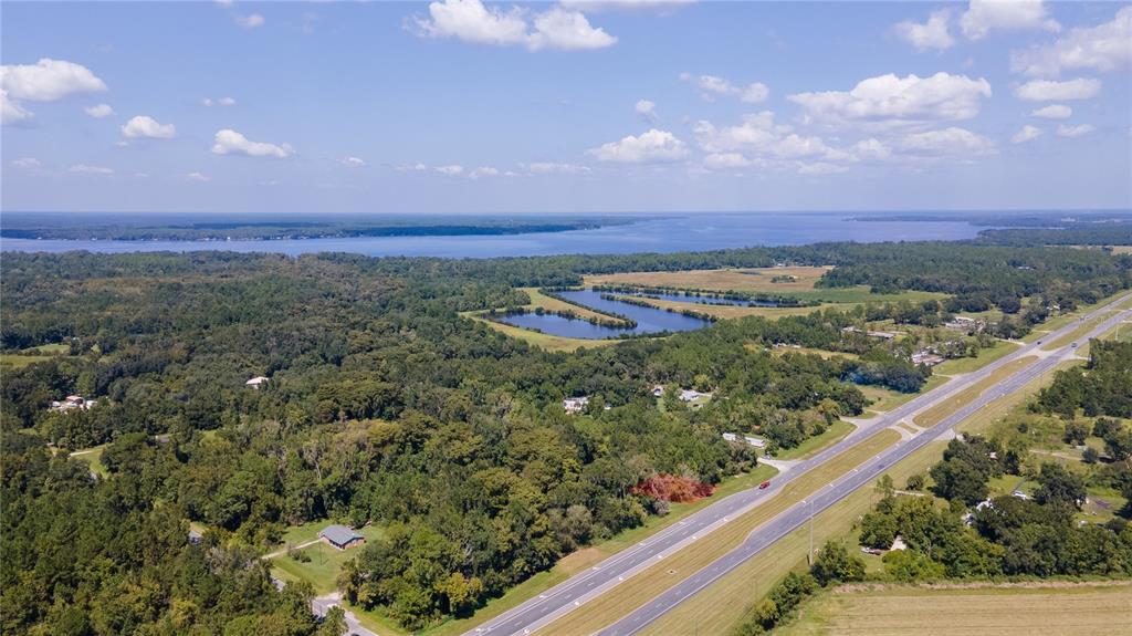 An aerial view shows a highway running alongside a wooded area with ponds and water — 421 STATE ROAD 207 ROAD, EAST PALATKA, FL