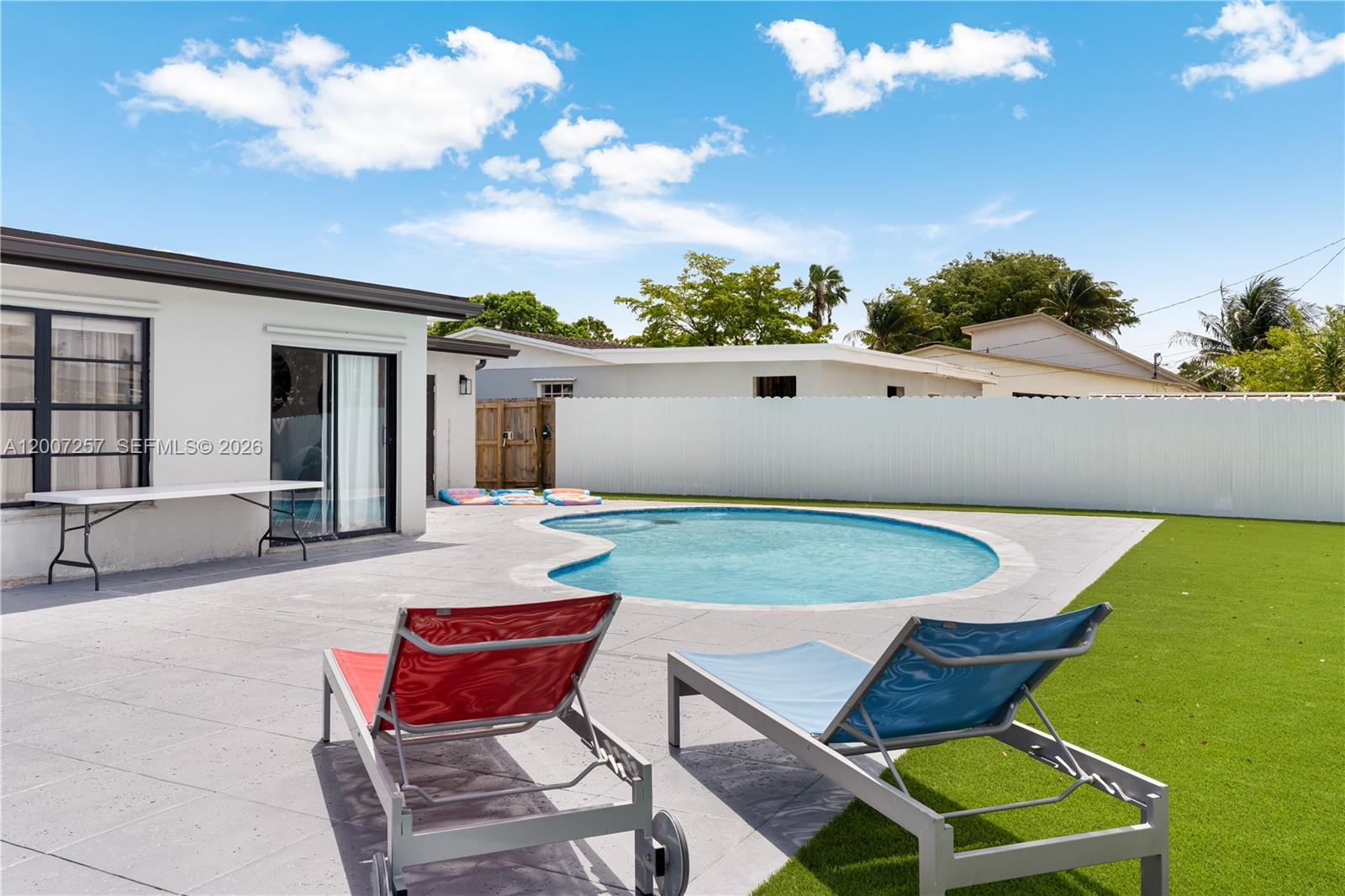 A backyard features a swimming pool, a concrete patio, and two lounge chairs — 7051 Tyler St, Hollywood FL 33024, HOLLYWOOD, FL