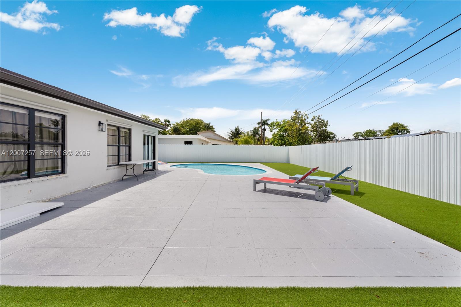 A backyard features a swimming pool, a gray patio, and two lounge chairs — 7051 Tyler St, Hollywood FL 33024, HOLLYWOOD, FL