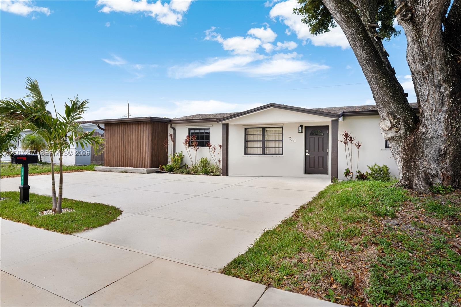 A single-story house with a white exterior, dark trim, and a large concrete driveway — 7051 Tyler St, Hollywood FL 33024, HOLLYWOOD, FL