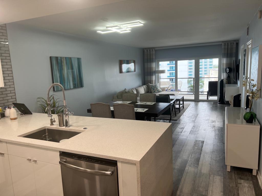 A kitchen island with a sink overlooks an open-concept dining and living area with balcony access — 1500 S Ocean Boulevard # 907, Pompano Beach FL 33062, POMPANO BEACH, FL
