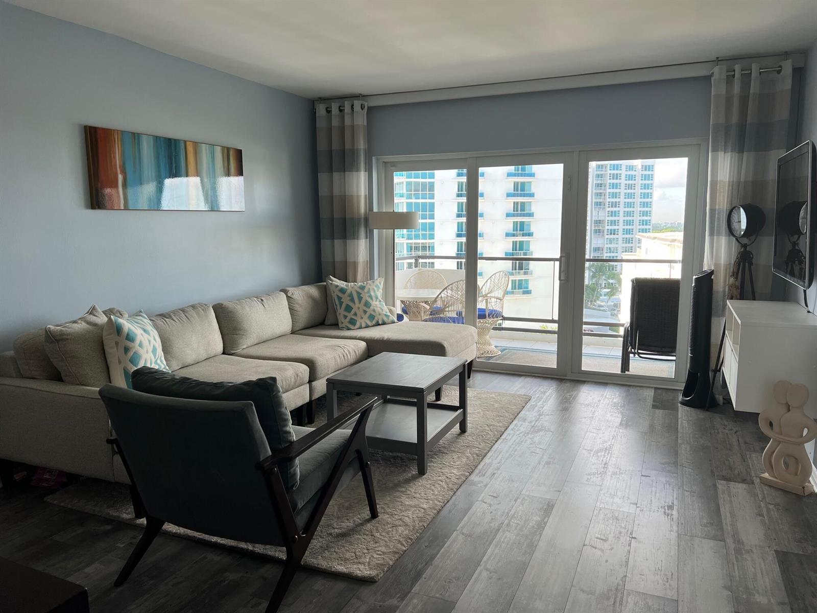 A living room features a sectional sofa, a coffee table, and a balcony with oceanfront views — 1500 S Ocean Boulevard # 907, Pompano Beach FL 33062, POMPANO BEACH, FL