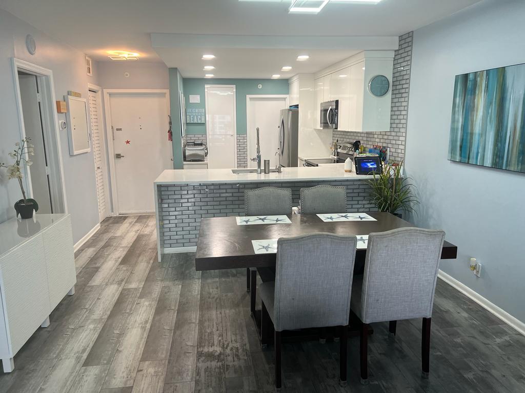 A dining area with a dark table and grey chairs sits before a tiled kitchen island — 1500 S Ocean Boulevard # 907, Pompano Beach FL 33062, POMPANO BEACH, FL