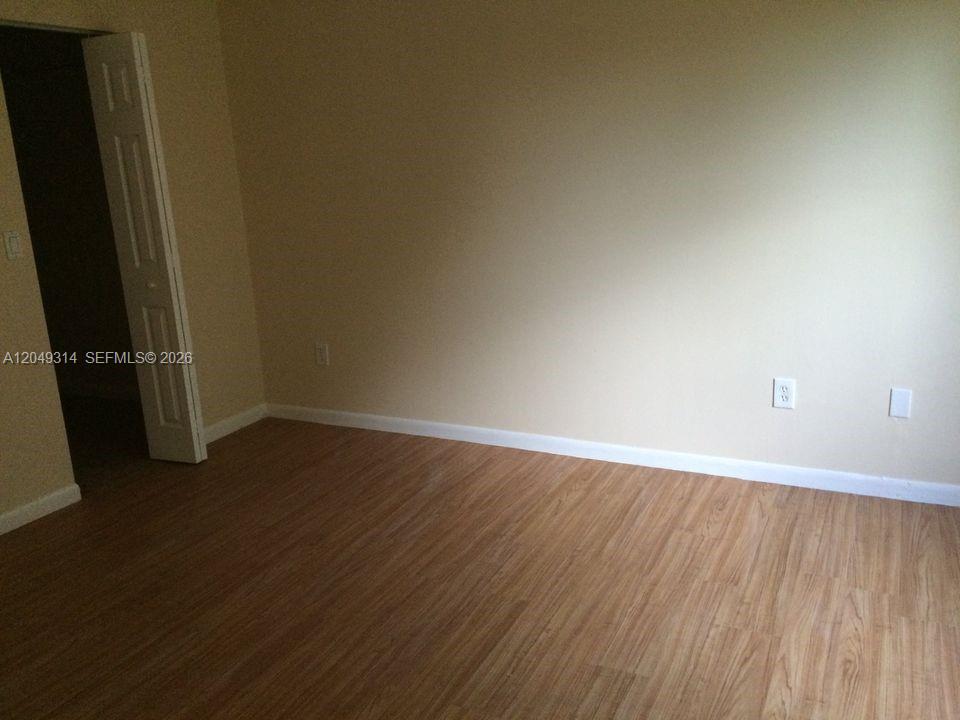 An empty room features light-colored walls, white trim, and wood-look laminate flooring — 861 NE 207th Ln # 14, Miami FL 33179, MIAMI, FL