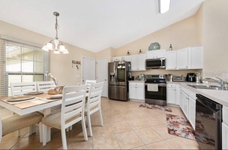 A kitchen and dining area with white cabinets, stainless steel appliances, and light tile flooring — 538 LAKEVIEW COURT, KISSIMMEE, FL