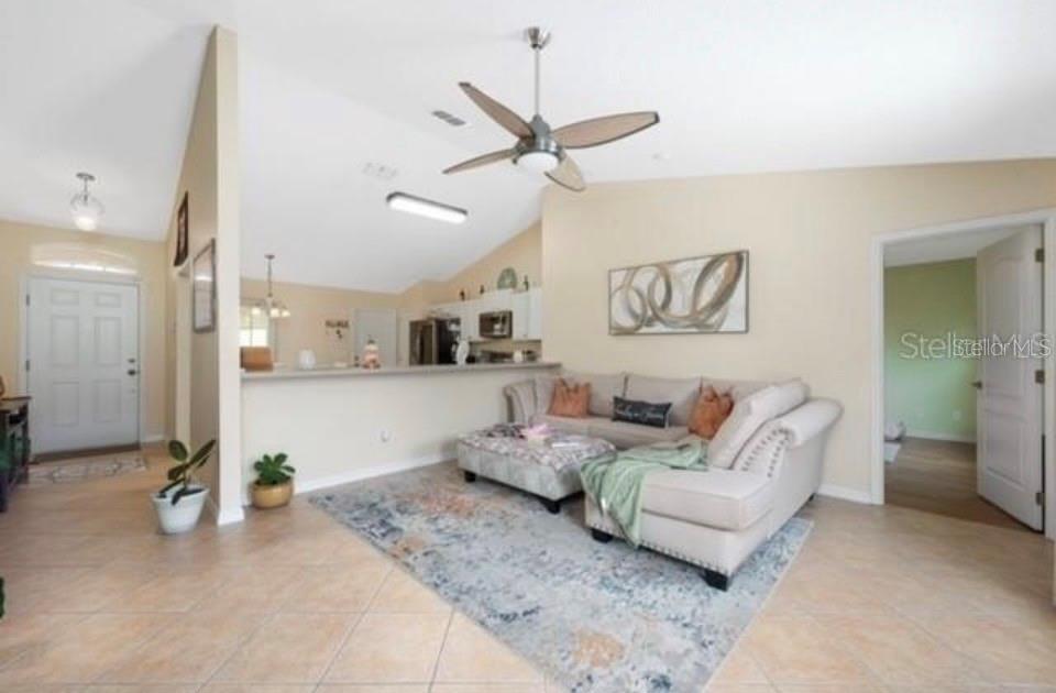 A living room with tile floors, a ceiling fan, and an open kitchen counter — 538 LAKEVIEW COURT, KISSIMMEE, FL