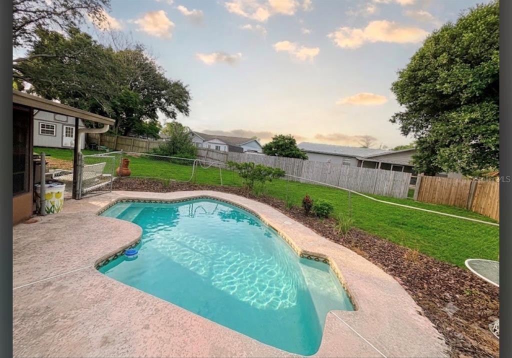 A backyard features a swimming pool with a concrete deck and a fenced grassy lawn — 93 GLASS COURT, PORT ORANGE, FL