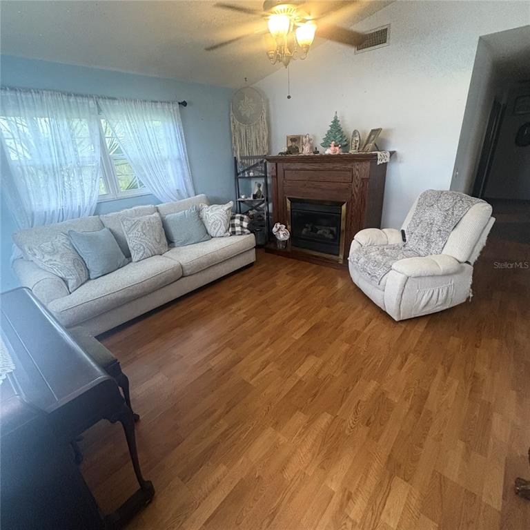 A living room features a beige sofa, a white recliner, and a wooden fireplace — 93 GLASS COURT, PORT ORANGE, FL