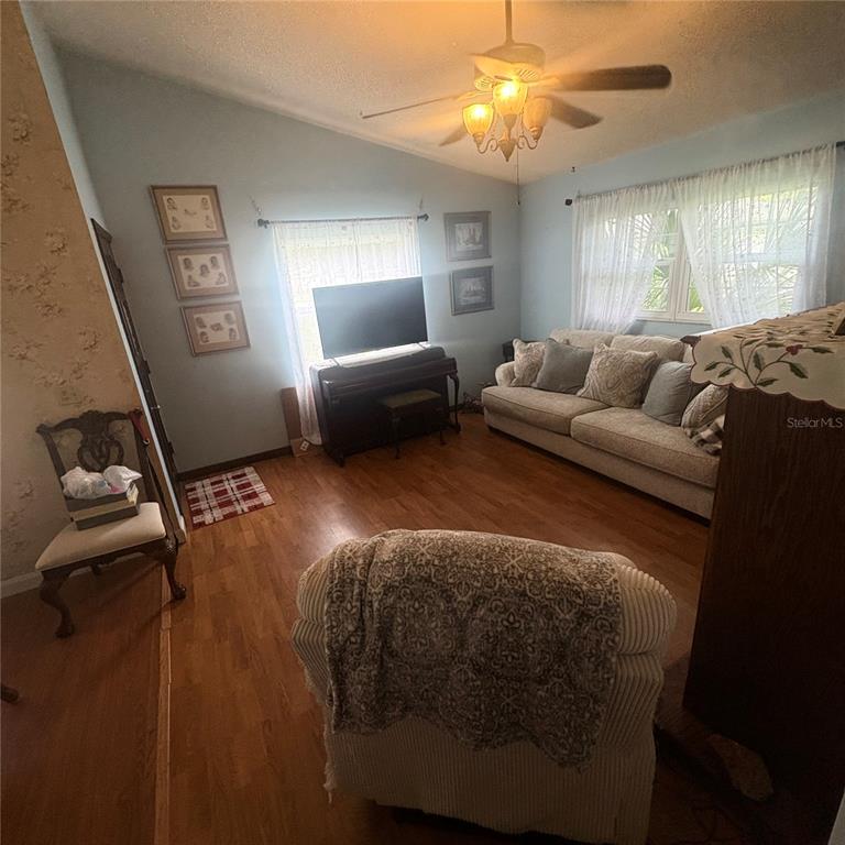 A living room features light blue walls, hardwood floors, a white sofa, and a ceiling fan — 93 GLASS COURT, PORT ORANGE, FL