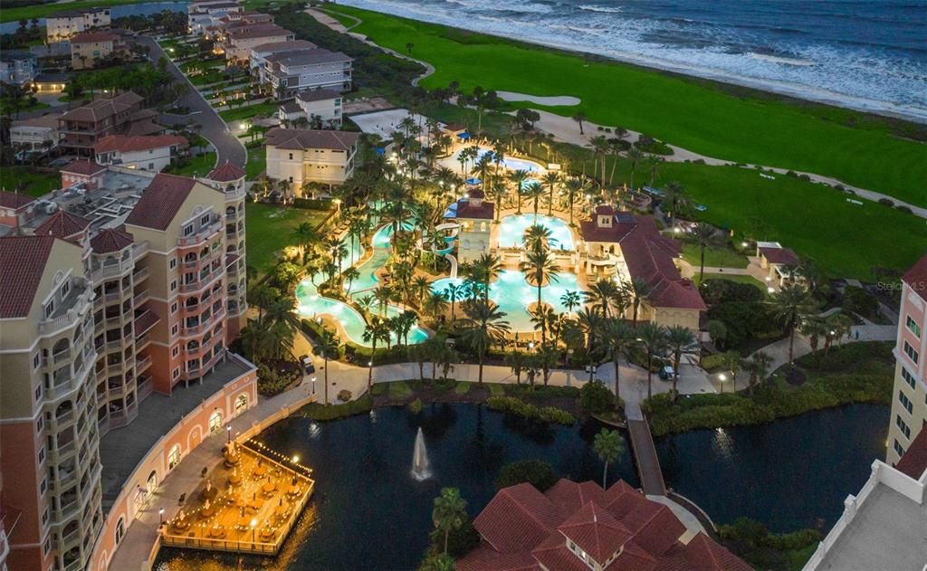 An aerial view shows a resort complex with swimming pools, palm trees, and oceanfront grounds — 200 OCEAN CREST DRIVE UNIT 312, PALM COAST, FL