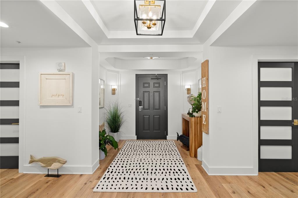 A bright entryway features a dark front door, light wood flooring, and a patterned rug — 200 OCEAN CREST DRIVE UNIT 312, PALM COAST, FL