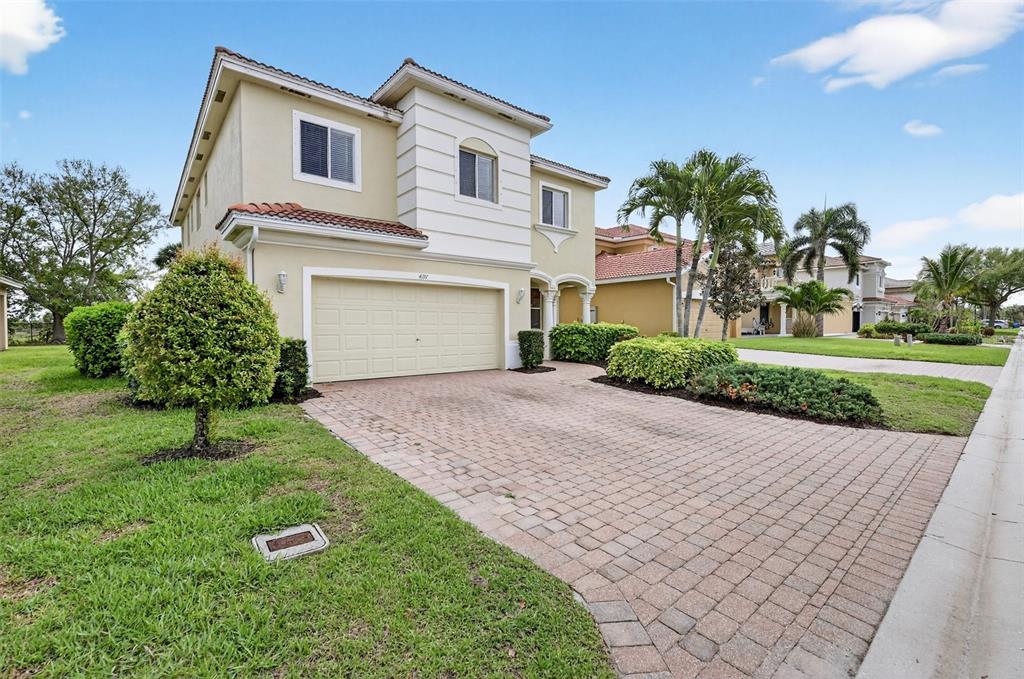 A two-story suburban house with a beige stucco exterior and a paved driveway — 4197 RIVER BANK WAY, PUNTA GORDA, FL