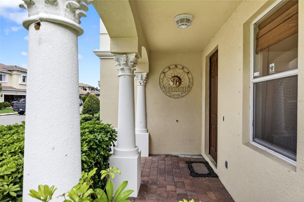 A covered front entryway features stone pavers, decorative columns, and a sun-themed welcome sign — 4197 RIVER BANK WAY, PUNTA GORDA, FL