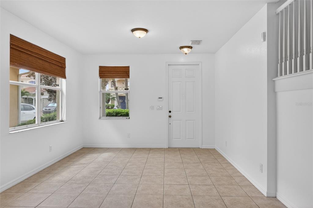 An empty room with tiled floors, white walls, two windows with blinds, and a door — 4197 RIVER BANK WAY, PUNTA GORDA, FL