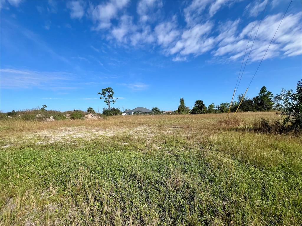 A wide, grassy vacant lot under a blue sky with scattered clouds — 1515 NE 32ND LANE, CAPE CORAL, FL