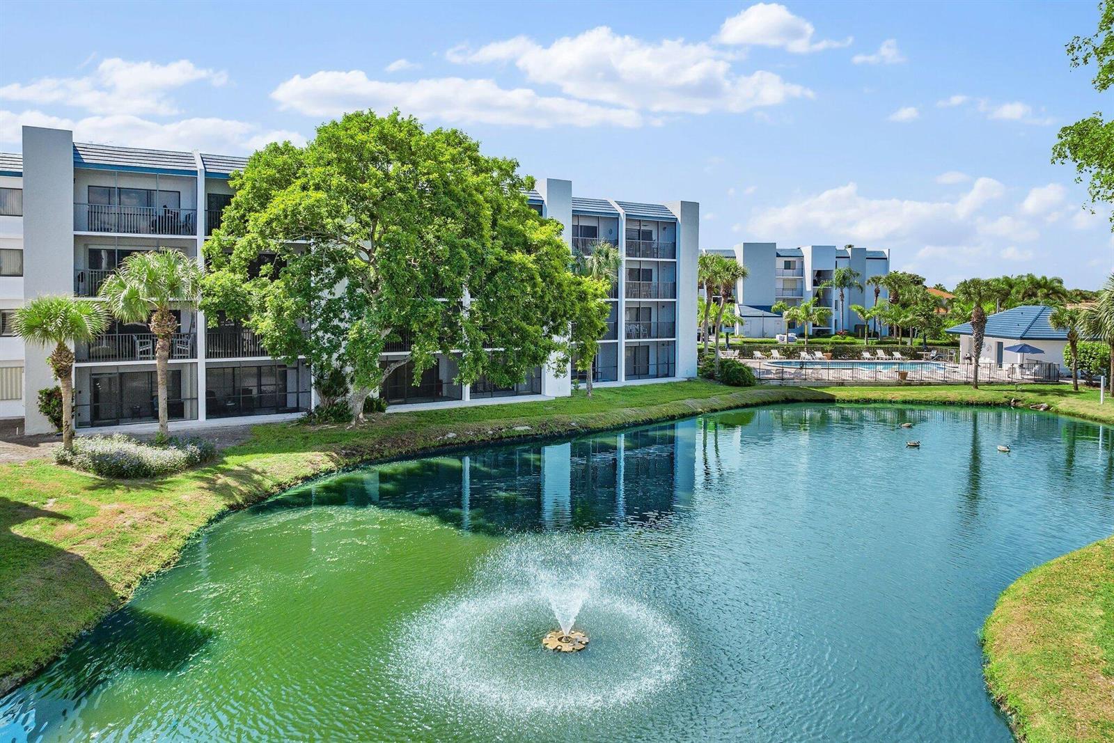 A multi-story apartment building overlooks a pond with a fountain and a swimming pool — 1605 S Us Hwy 1 # A306, Jupiter FL 33477, JUPITER, FL