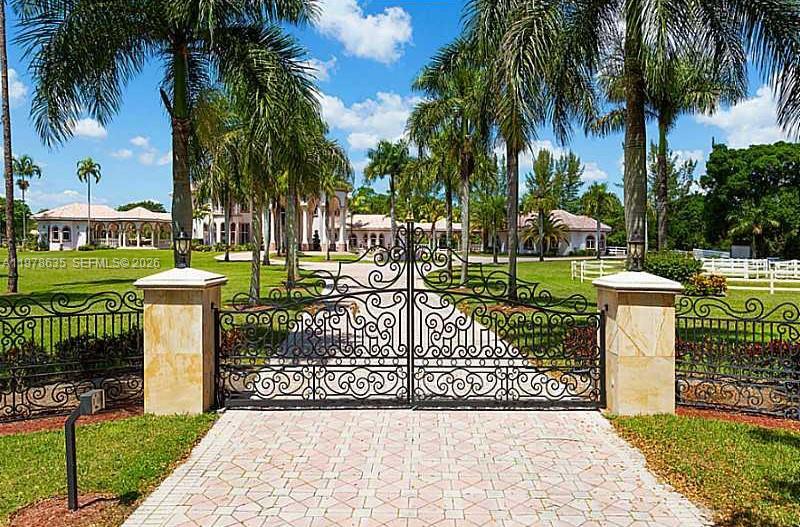 A wrought iron gate stands at the entrance of a driveway leading to a mansion — 21579 Cartagena Dr, Boca Raton FL 33428, BOCA RATON, FL