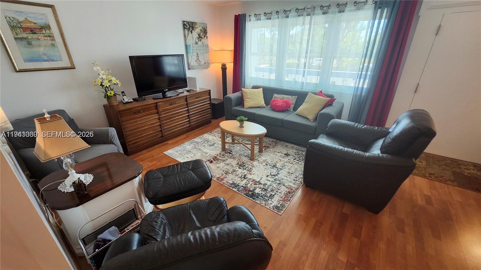 A living room features a grey sofa, a leather armchair, a wooden dresser, and hardwood floors — 2112 Newport U # 2112, Deerfield Beach FL 33442, DEERFIELD BEACH, FL