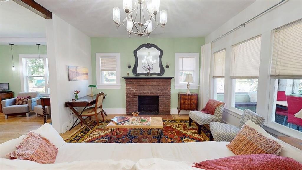 A living room features a brick fireplace, a chandelier, and a large patterned area rug — 2010 S MAPLE AVENUE, SANFORD, FL
